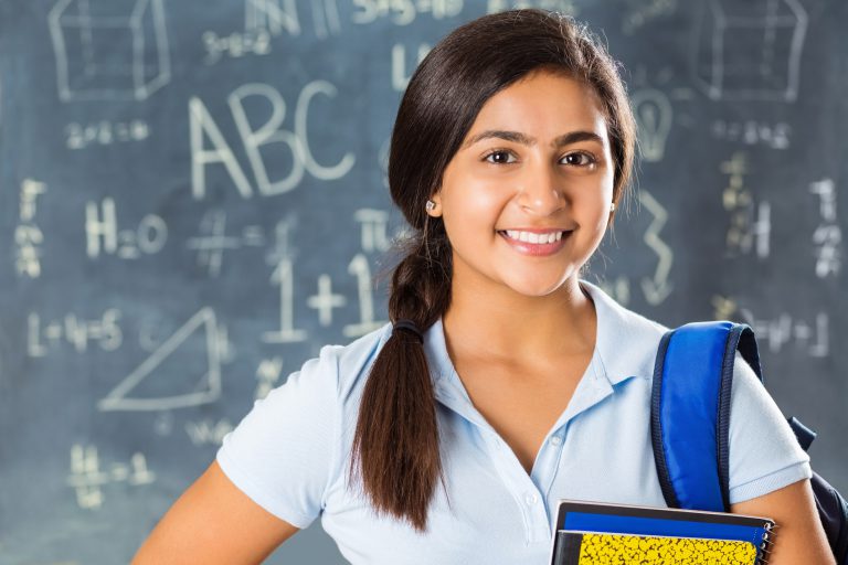 Portrait of pretty Indian high school student in classroom